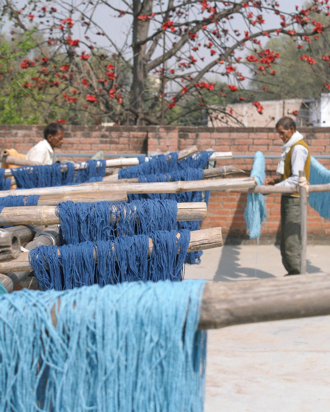 Blue yarn hanging on a rack with people in the background